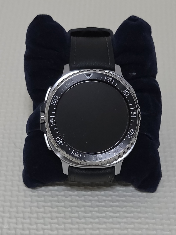 Galaxy Watch 8 Classicを紺色のベルベットクッションに乗せて撮影した写真。ベゼル付きの本体と黒いレザーバンドが写っている